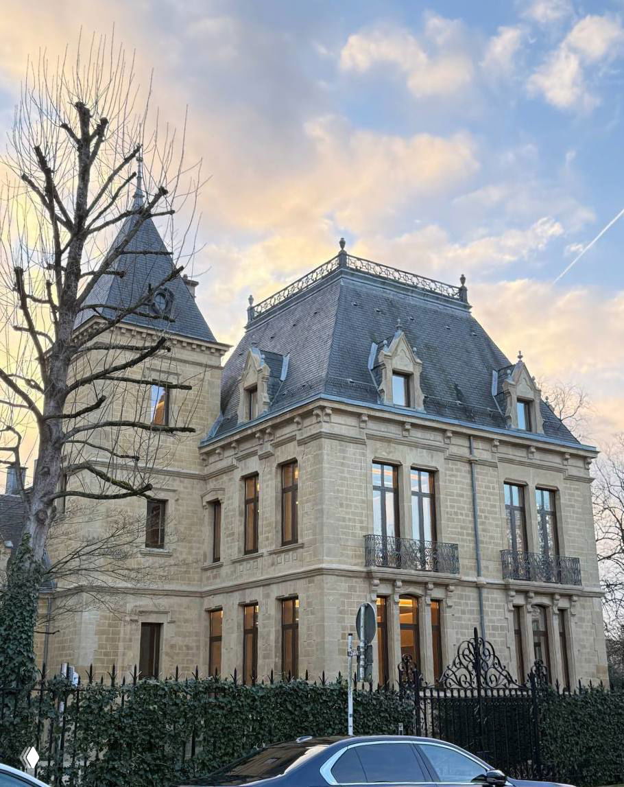 Каменный особняк с декоративной оградой и нарядным фасадом при мягком дневном свете, архитектура в классическом европейском стиле.