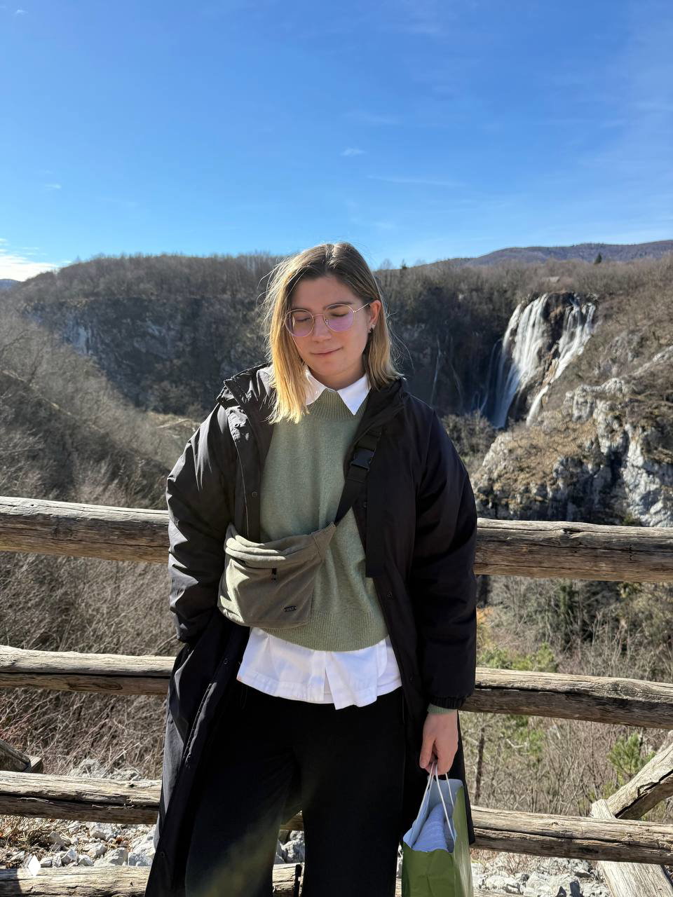 Портрет автора на фоне плато и водопада Плитвицких озёр; солнечный день и видимый каскад на заднем плане создают атмосферу путешествия.