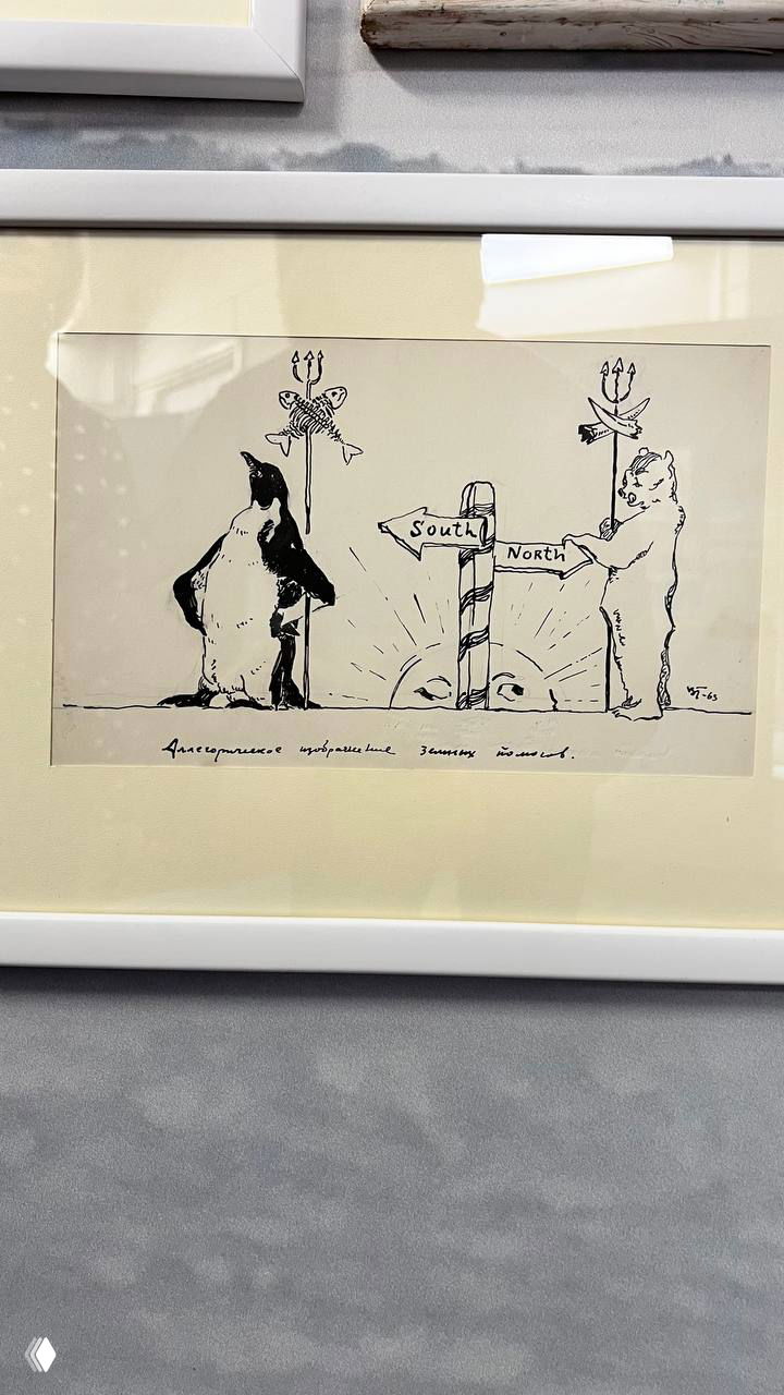 Карикатура в рамке с пингвином и белым медведем у указателя «South / North» — юмористический рисунок в экспозиции музея.