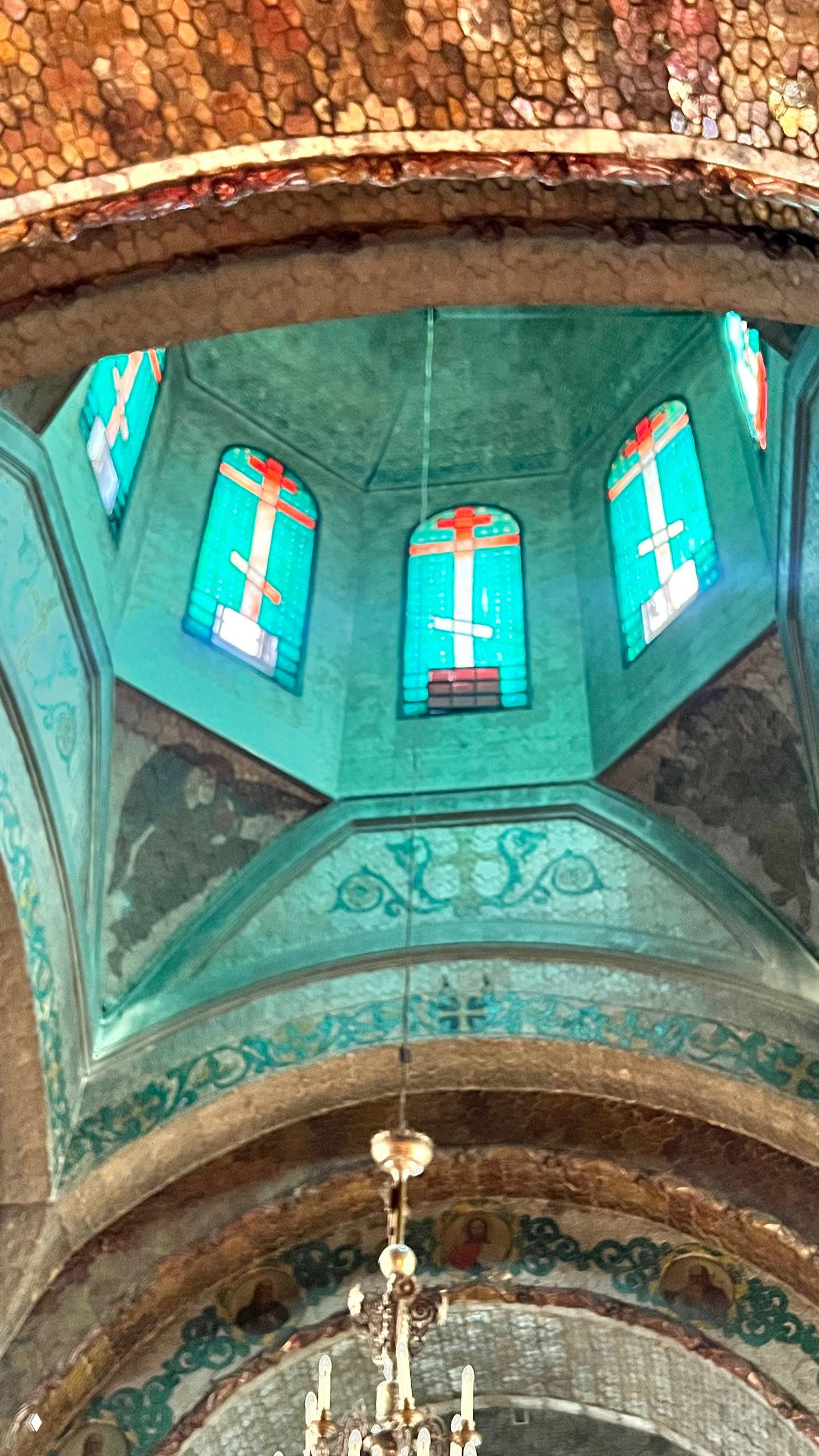 Рваная и треснувшая декоративная поверхность свода над витражным окном: структура покрытия и цветные стекла внизу кадра.