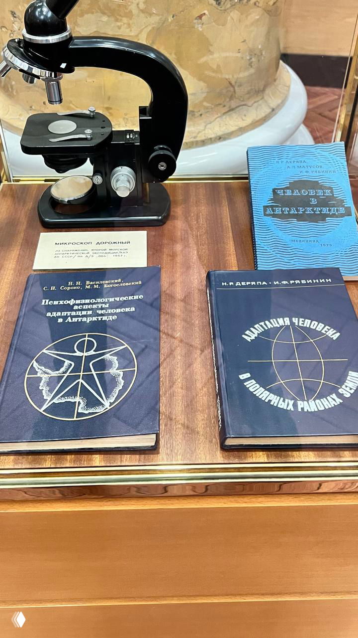 Витрина с научными пособиями и микроскопом: старые брошюры по адаптации человека в Антарктиде, издания 1970-х годов.