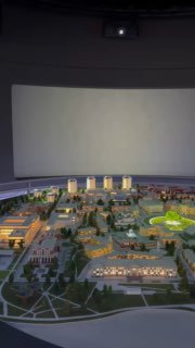 Макет-панорама внутри музея «Атом»: уменьшенная городская экспозиция на подиуме на фоне большого полукруглого экрана и тёмного зала.