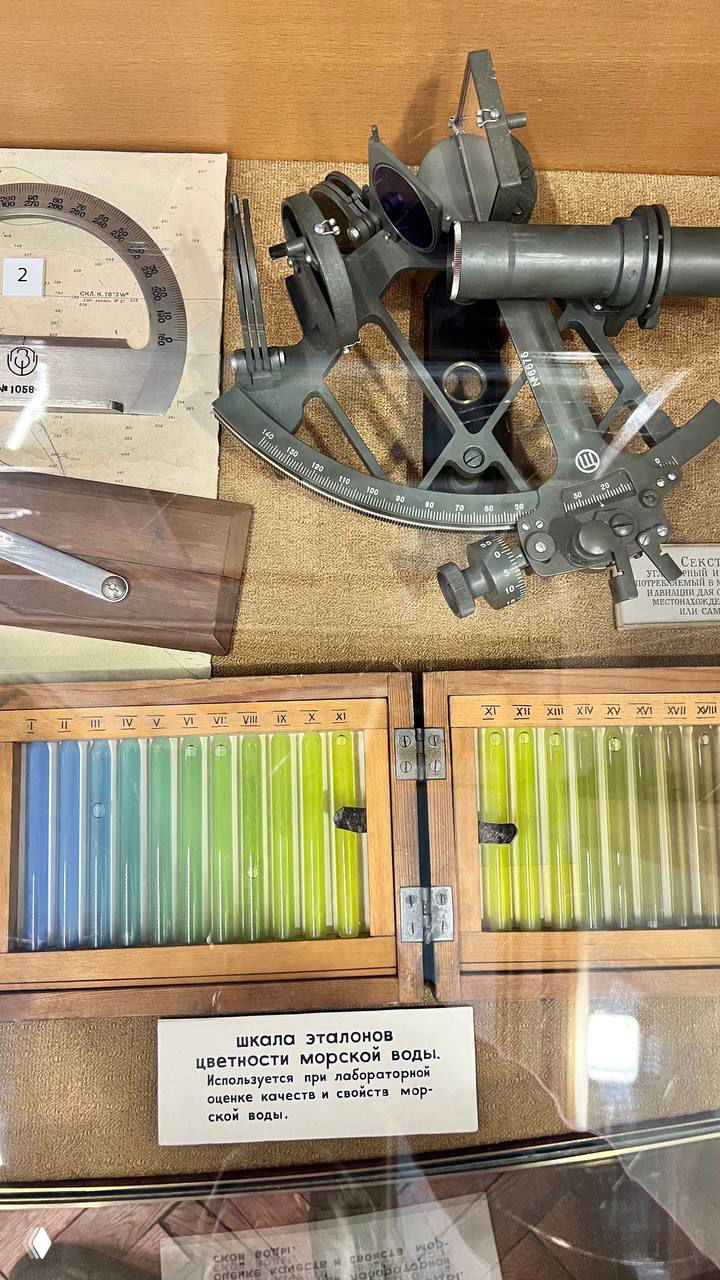 Навигационные приборы и набор эталонов цветности морской воды в музейной витрине: секстанты, шкалы и цветные образцы для лабораторной оценки.