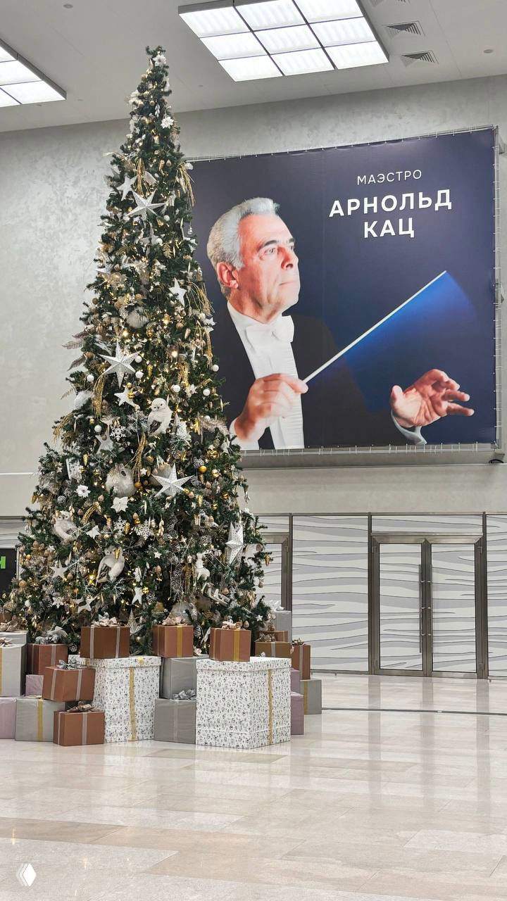 Внутренний холл филармонии с большой рождественской ёлкой и крупным плакатом с портретом маэстро Арнольда Каца на стене.