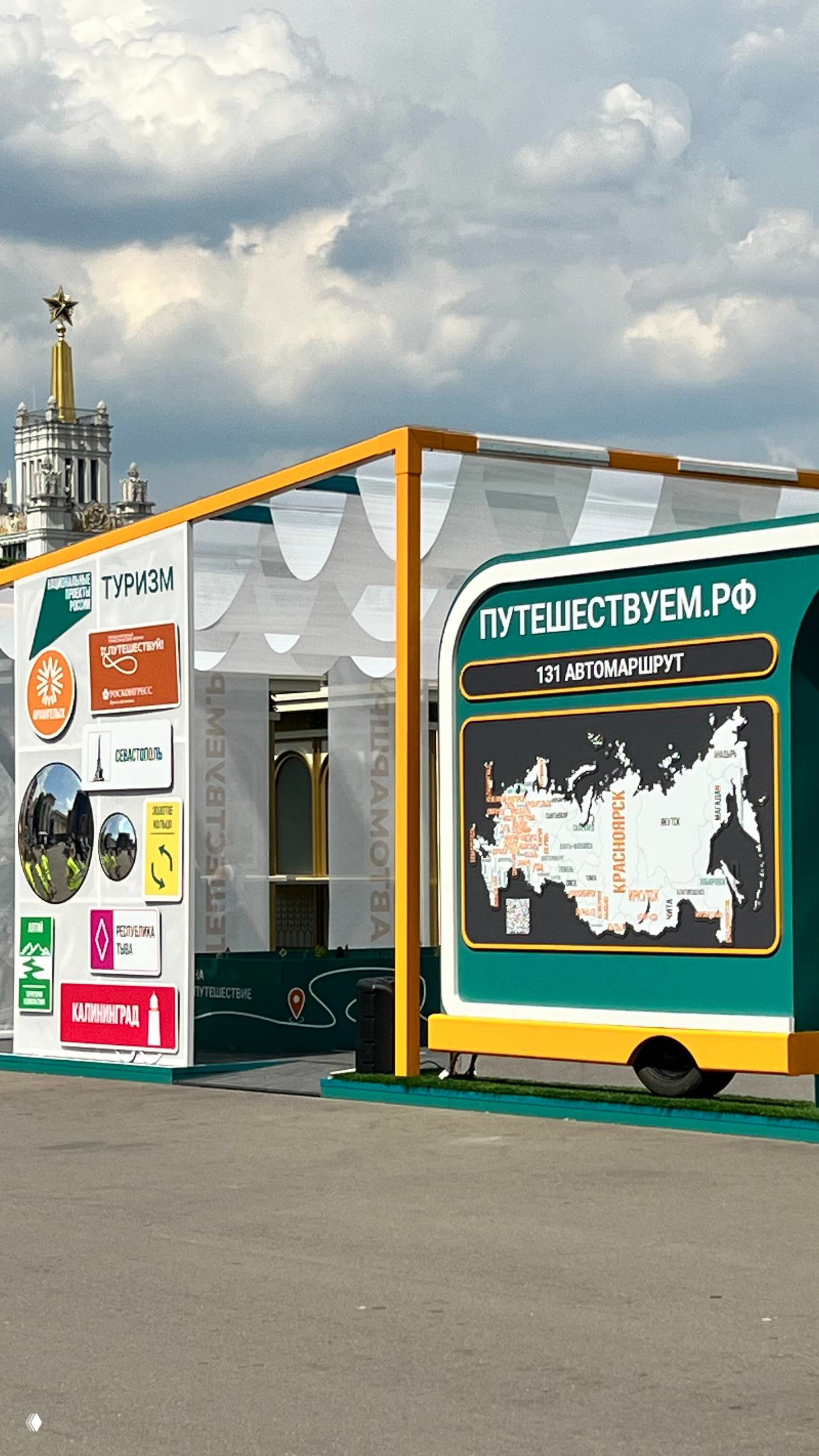 Стенд «Путешествуем.РФ» с картой маршрутов и навигацией на ярко оформленной площадке, на заднем плане видна золотая шпиль ВДНХ.