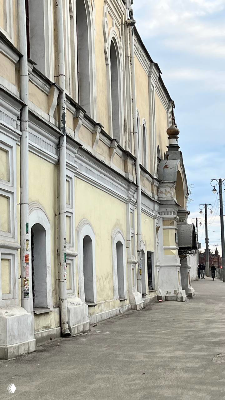 Длинный фасад старого здания с арочными нишами и бледно-жёлтой штукатуркой — архитектурный ряд центральной улицы Владимира.