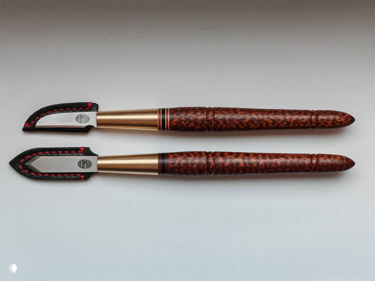 Два ножа в продольной проекции на белом фоне — видно тонкую обработку, полировку и фактуру снейквуда по всей длине