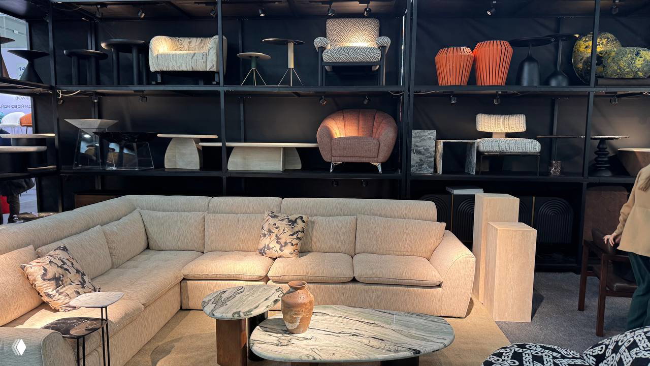 Чёрное мягкое кресло на ковровом покрытии выставочного стенда — компактная модель с кожаной обивкой и металлическим каркасом.