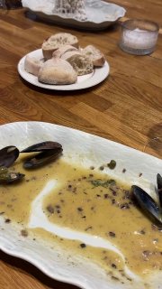 Тарелка с остатками пасты и мидиями на столе; кусочки хлеба и соус на фоне, интерьер кафе One Chef Studio и детали сервировки