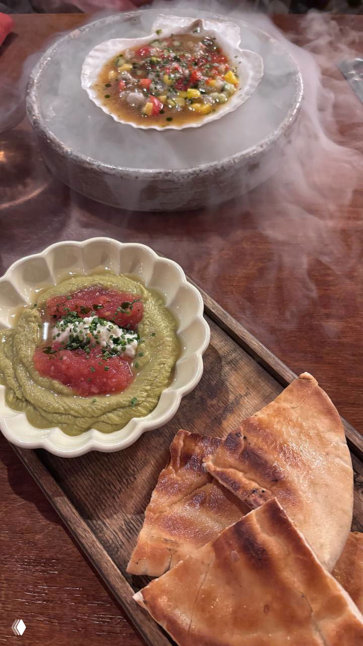 Подача блюда с дымом сухого льда: ракушка с морепродуктами на охлаждённой подставке и яркая закуска рядом — эффектная презентация в Single.