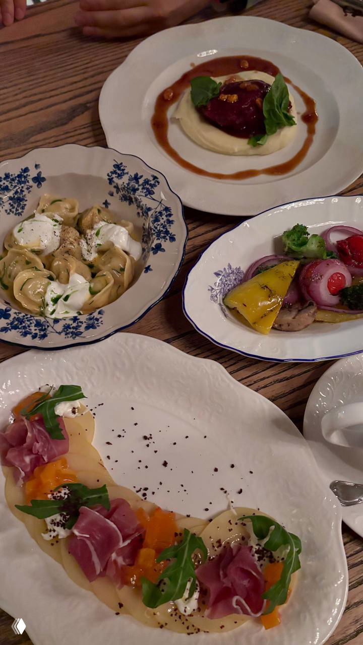 Набор тарелок с закусками и основным блюдом на деревянном столе — смесь авторских и классических русских мотивов в подаче