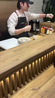 Кадр видеоподачи: шеф за барной стойкой в фартуке готовит и подает блюда гостям прямо на глазах, атмосферный момент сета.