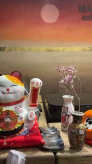 Декор на стойке: манэки-нэко, вазы и фигурки на фоне фирменного панно Masse Omakase — финальный вид пространства ресторана.