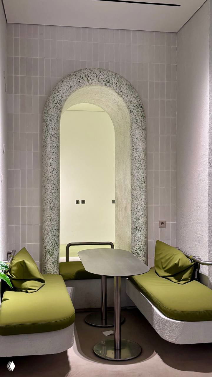 Ниша с арочным проёмом в паста-баре Means: два небольших столика, оливковые подушки, текстурная штукатурка и приглушённое освещение для камерной атмосферы.