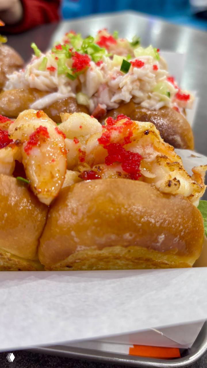 Макрофото булочки Bolo с креветками: прожаренные креветки, икра и сочная бриошь в крупном плане, видно текстуру теста и начинки.