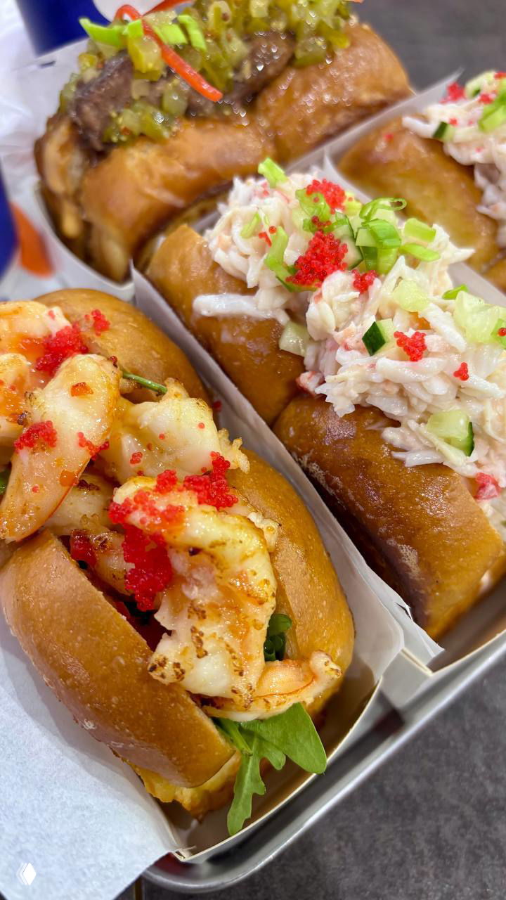 Ещё один ракурс лотка с булочками Bolo: бриоши с креветками, крабом и зеленью, аккуратно уложенные в бумажные контейнеры на подносе.