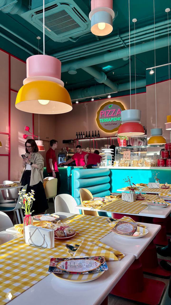 Миска супа-пюре в полосатой тарелке с оливковым маслом и хрустящей лепешкой рядом, подана на столе с желтым мотивом посуды.