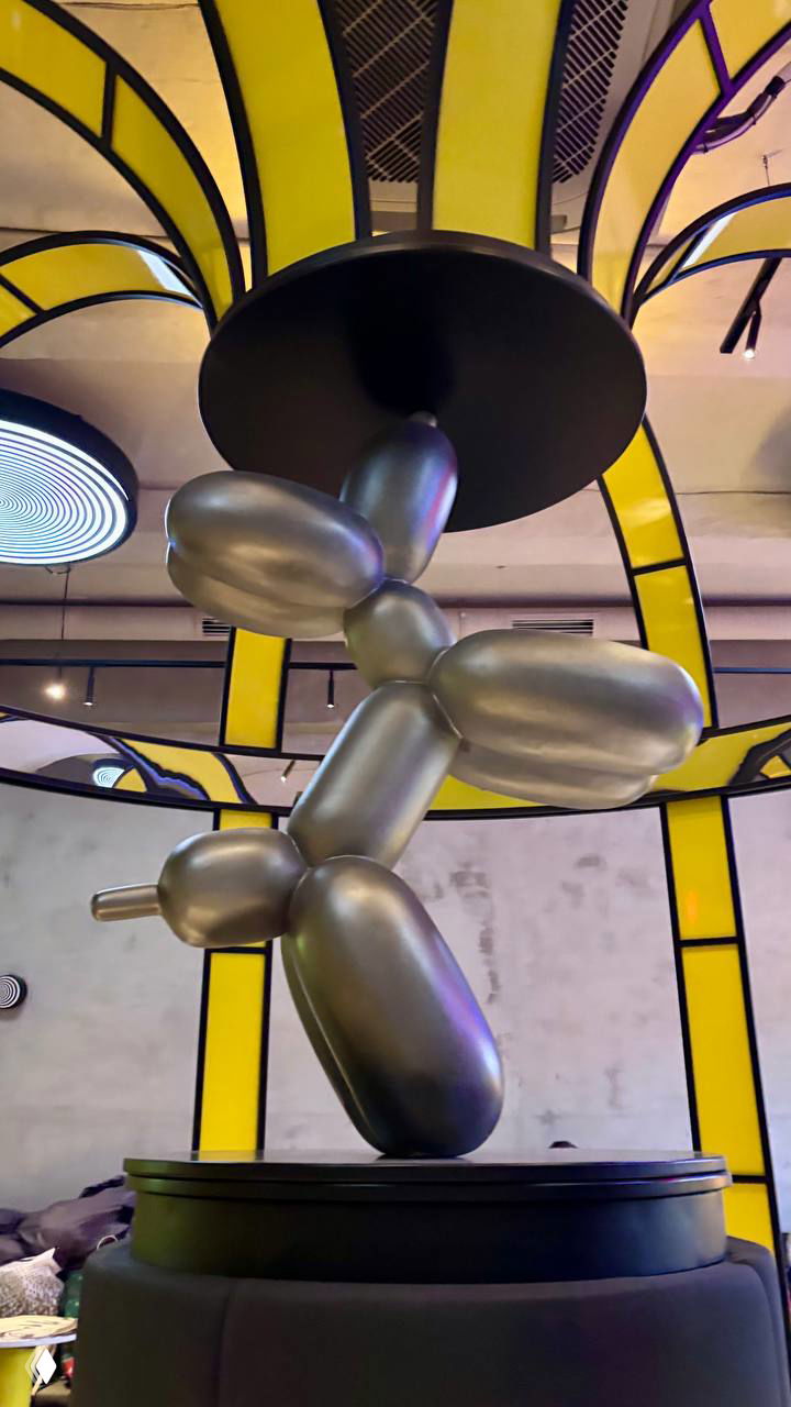 Декоративная скульптура в виде шариковой фигуры из металлика под центральной частью карусели, вид снизу на интерьер и подсветку.