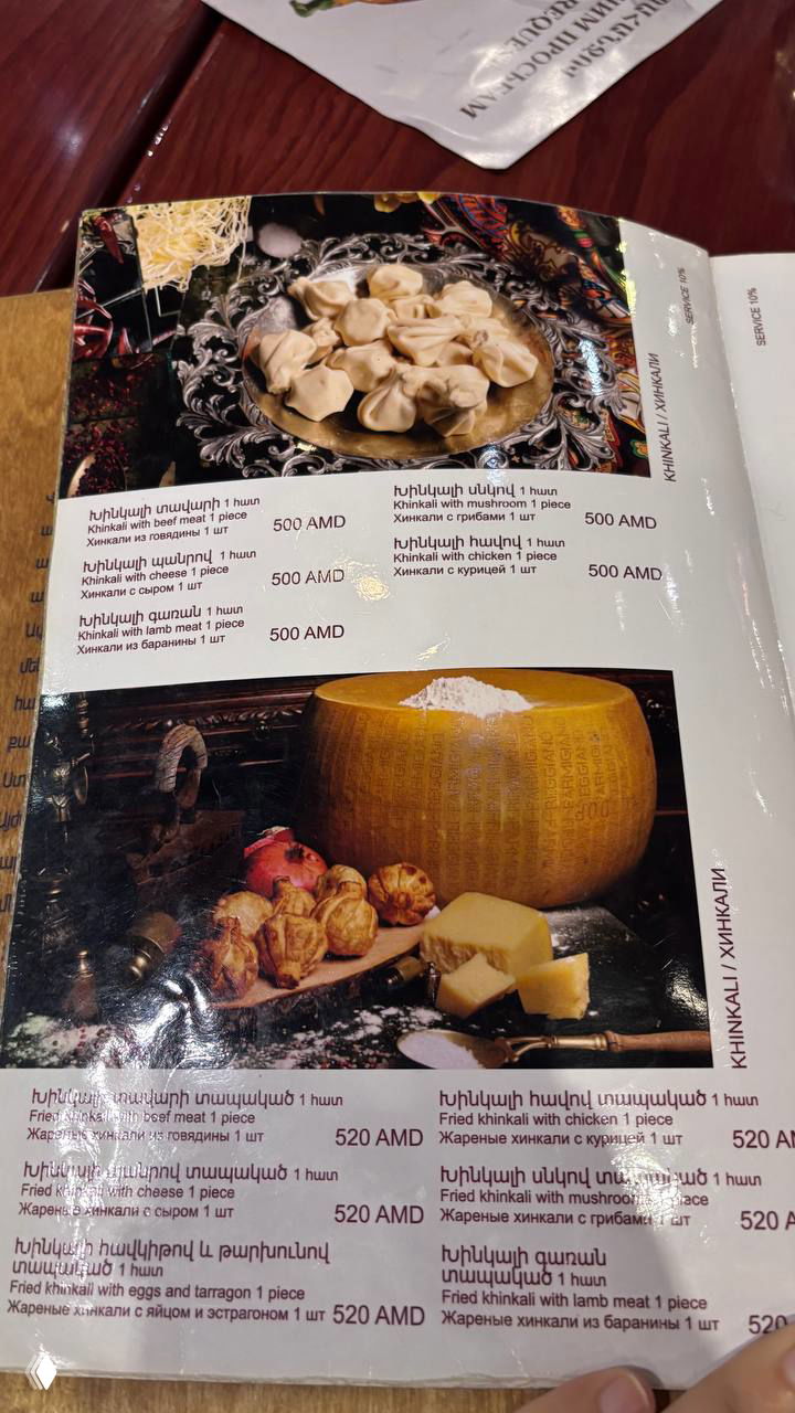 Фотография меню ресторана с крупным изображением хинкали и ценами в AMD, страницы меню в кадре и оформление блюд на снимке.