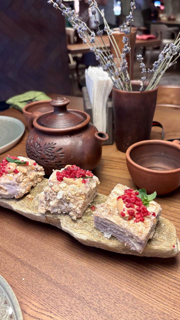 Крупный план столика с вязаной скатертью, деревянной посудой и атмосферной сервировкой внутри зала ресторана в ретро‑стиле.