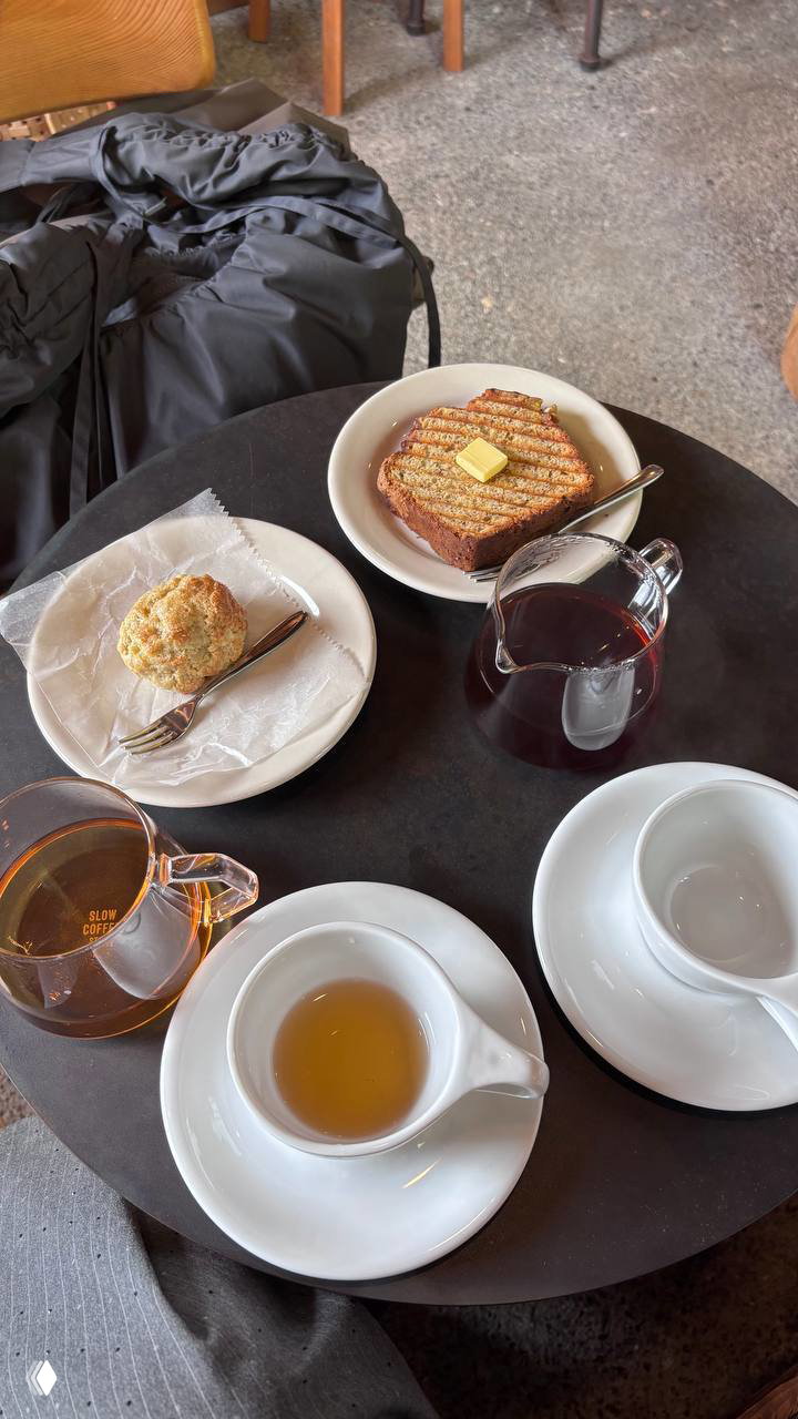 Кофейный столик с чашками, булочкой и тостом, графин с сиропом и керамическая посуда — натюрморт утренней подачи в японской кофейне.