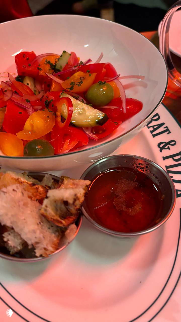 Салат из томатов и овощей в глубокой тарелке, рядом кусочки хлеба и дип — лёгкая закуска к пицце в Rusty Rat & Pizza.