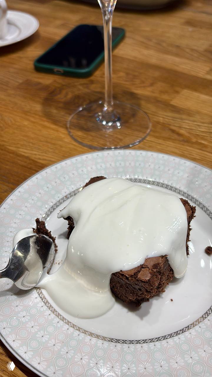 Десерт с растопленной сливочной прослойкой на фарфоровой тарелке рядом с бокалом вина — финальный кадр ужина в заведении.