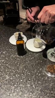 Руки баристы смешивают элементы и переливают жидкости в маленькие тарелки — набор инструментов и компонентов для пейрингов в кадре.