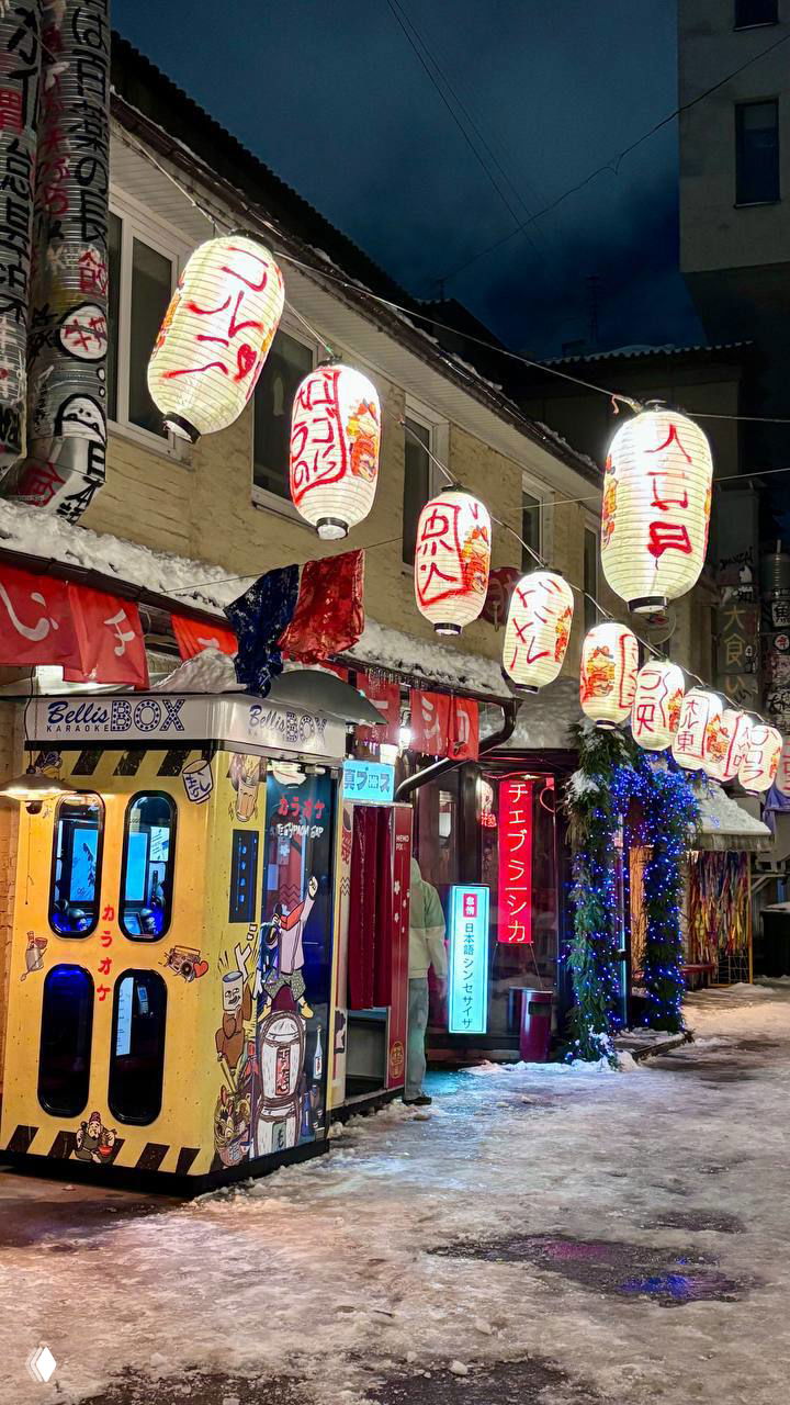 Улица с японскими фонариками и маленькими вывесками заведений, заснеженная тротуарная плитка и киоски — атмосферный фасад одного из ресторанов в Москве.