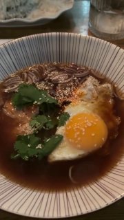 Порция рамена в глубокой пиале с жареным яйцом, зеленью и тёмным бульоном — кадр рамeна из меню One Chef Studio.