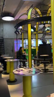 Общий вид внутреннего пространства бара: карусельные конструкции с арками, низкие столики и стулья по кругу в минималистичном стиле.