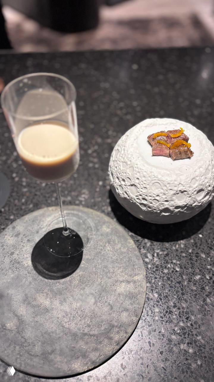 Фужер с холодной подачей и небольшая порция мяса на текстурном белом блюде — элегантная подача и необычные формы посуды.