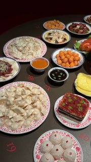 Стол с набором традиционных китайских блюд: пельмени, шарики и соусы на тарелках — демонстрация праздничной кухни в рамках выставки и культурного контекста.