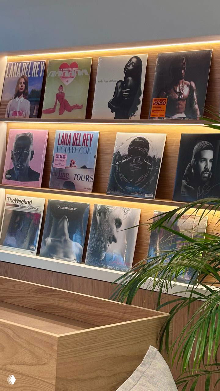 Ряды виниловых обложек и пластинок на полке в кофейне Fein: оформление зоны с музыкальной витриной и тёплой подсветкой