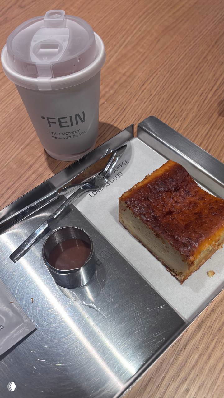 Подача кофе и десерта на металлическом подносе: бумажный стакан с логотипом °FEIN рядом с кусочком пирога и молочным соусом