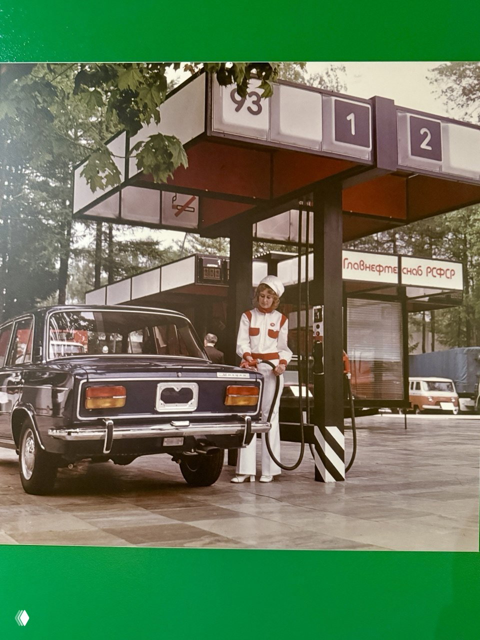 Архивная фотография на стенде: придорожная заправка с автомобилем и оператором в униформе — иллюстрация советской инфраструктуры и сервиса.
