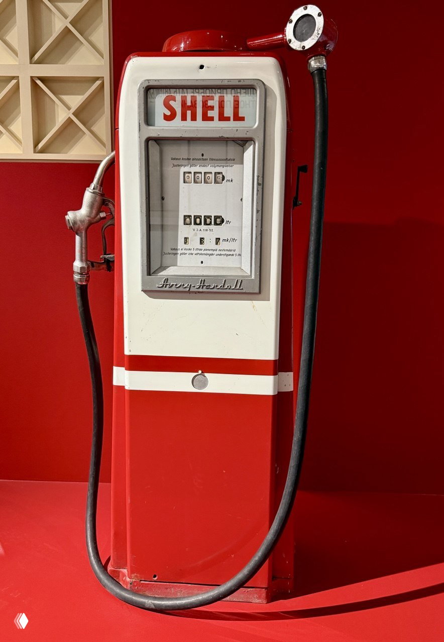 Ретро-бензоколонка марки Shell: красно‑белый корпус, измерительные шкалы и шланг — экспонат, показывающий дизайн колонок прошлых лет.