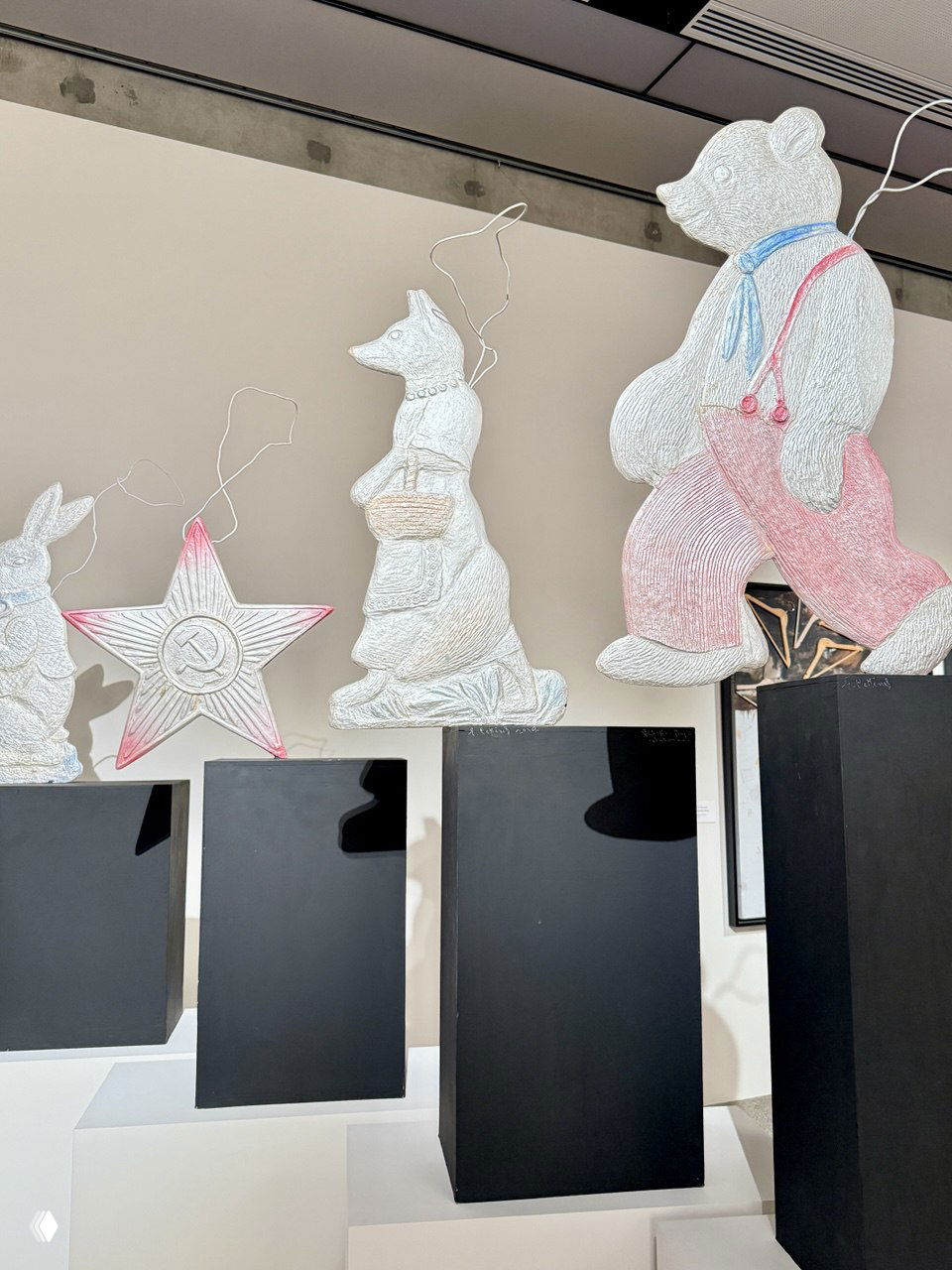 Инсталляция в зале: вырезанные белые фигуры животных на подиумах и декоративная звезда с советской символикой — современный арт-объект в экспозиции.