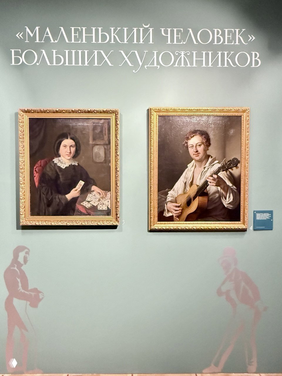 Стена экспозиции в Музее Тропинина: две оформленные портретные картины на зелёной стене и крупный заголовок выставки над ними.
