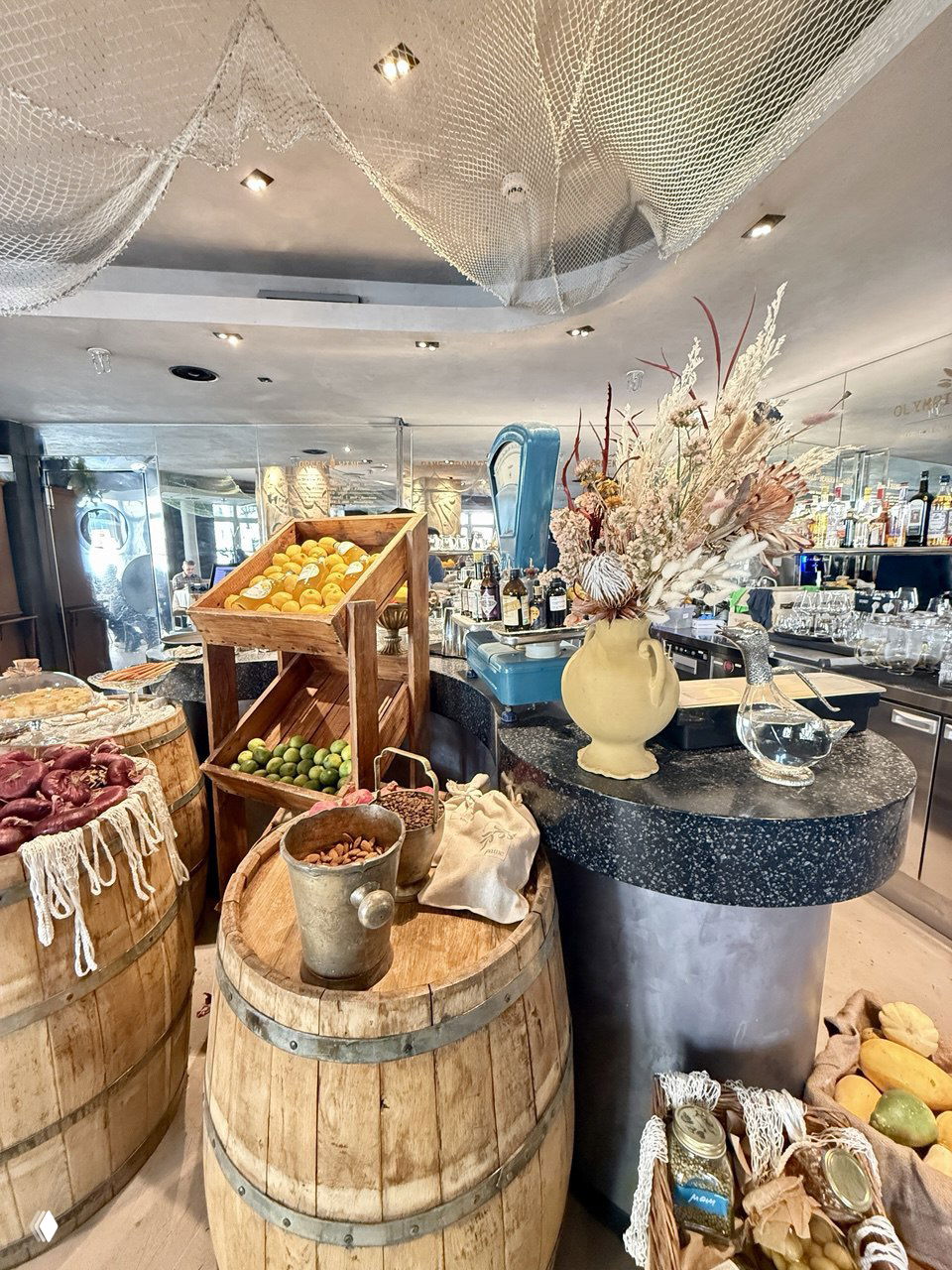 Барная зона Pame: бочки с цитрусами и лаймами, касса и декоративная композиция из сухоцветов на стойке — морской маркет-стиль.