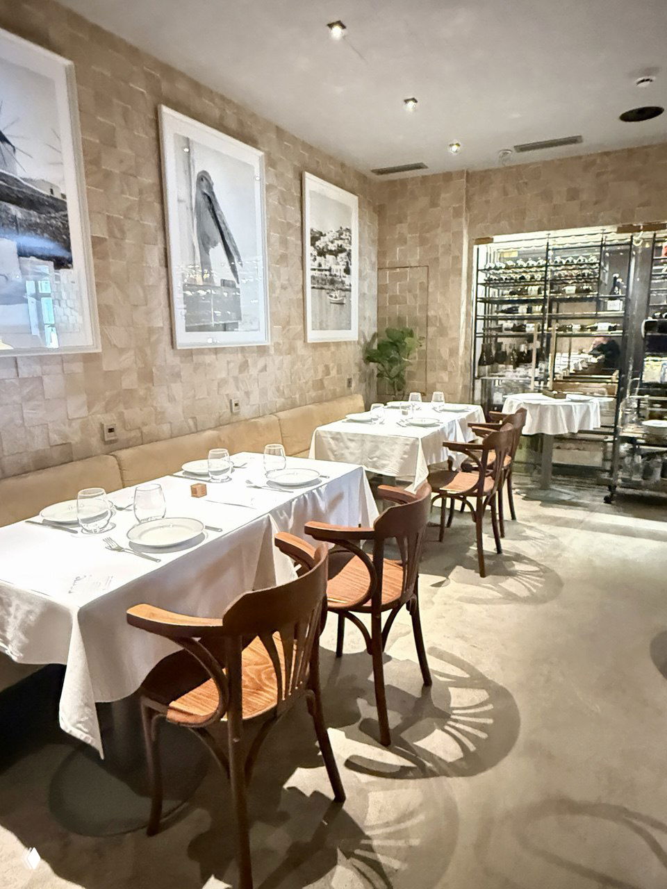 Обеденный зал Pame: столы с белыми скатертями, стулья и фотографии с морской тематикой на стенах, уютная светлая обстановка.