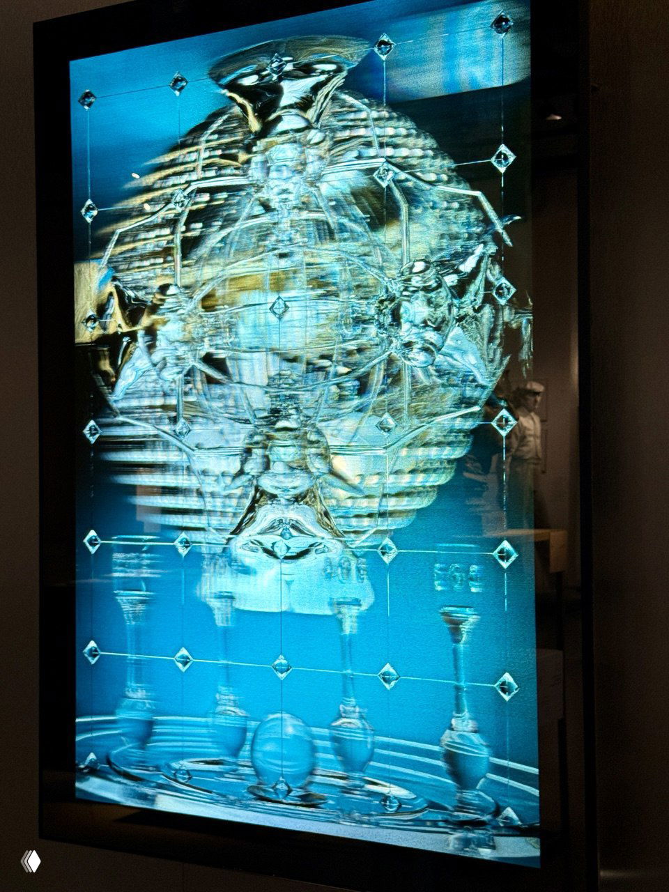 Инсталляция с подсвеченной стеклянной панелью и сложной геометрией отражений и декоративных элементов — современная часть экспозиции в тёмных тонах.