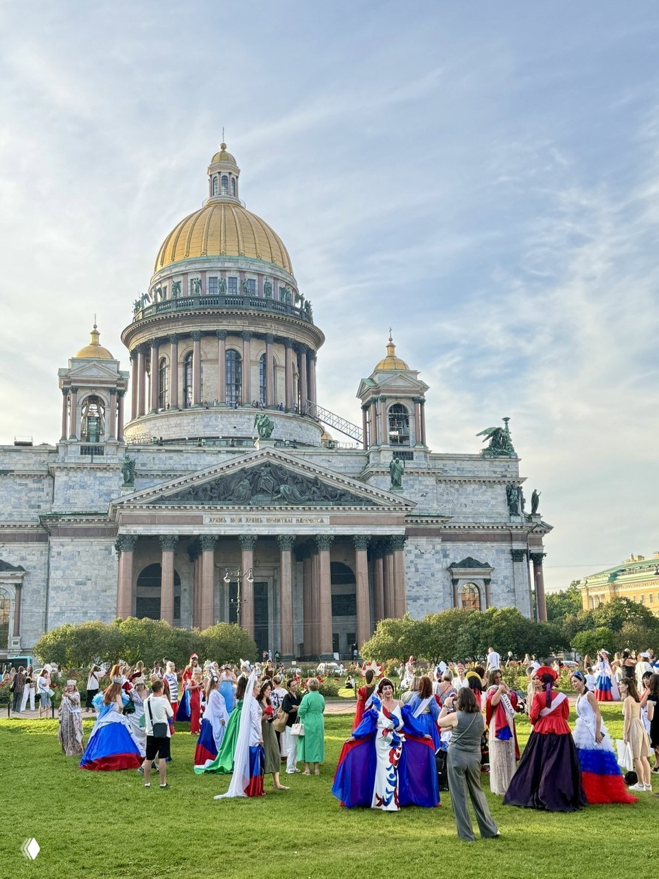 Большая группа людей в костюмах на газоне перед Исаакиевским собором — фестивальная сцена и архитектура на заднем плане.