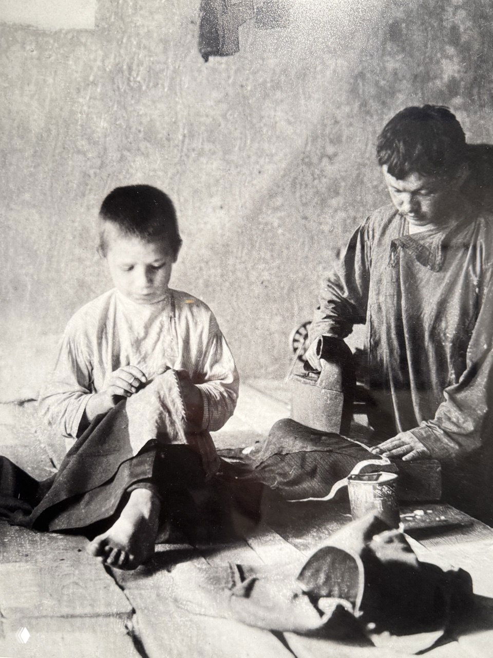 Документальная фотография детского труда: двое мальчиков шьют и гладят ткань в условиях ремесленной работы того периода в Москве, отражение социальной реальности.