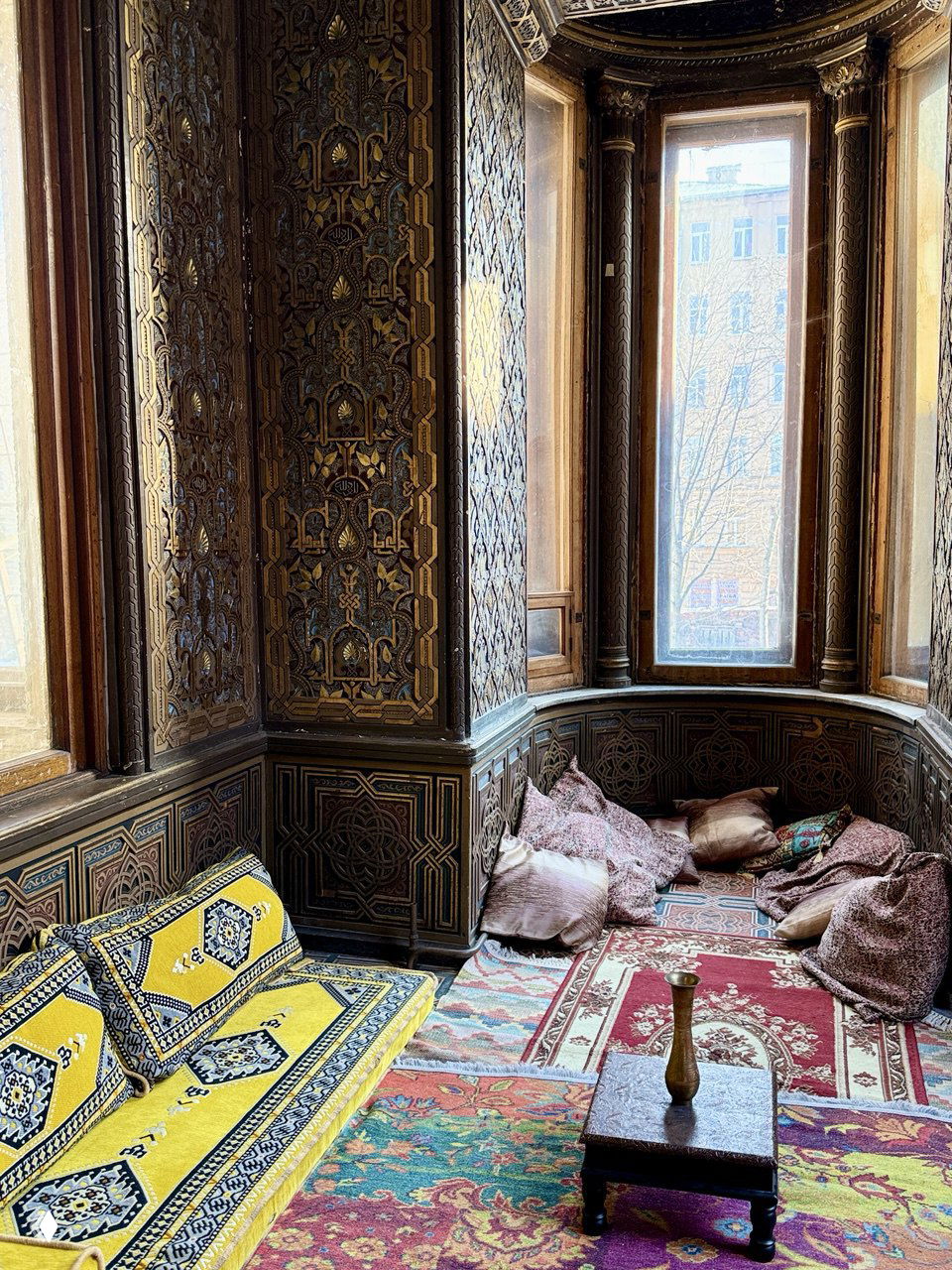 Уютный эркер с восточными тканями и подушками, ковры и низкий столик — экзотический уголок в одном из помещений особняка.