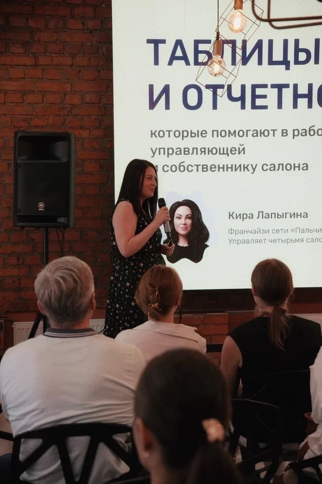 Презентация на сцене: ведущий у экрана рассказывает про процессы и инструменты, аудитория в креслах внимательно наблюдает и делает пометки.