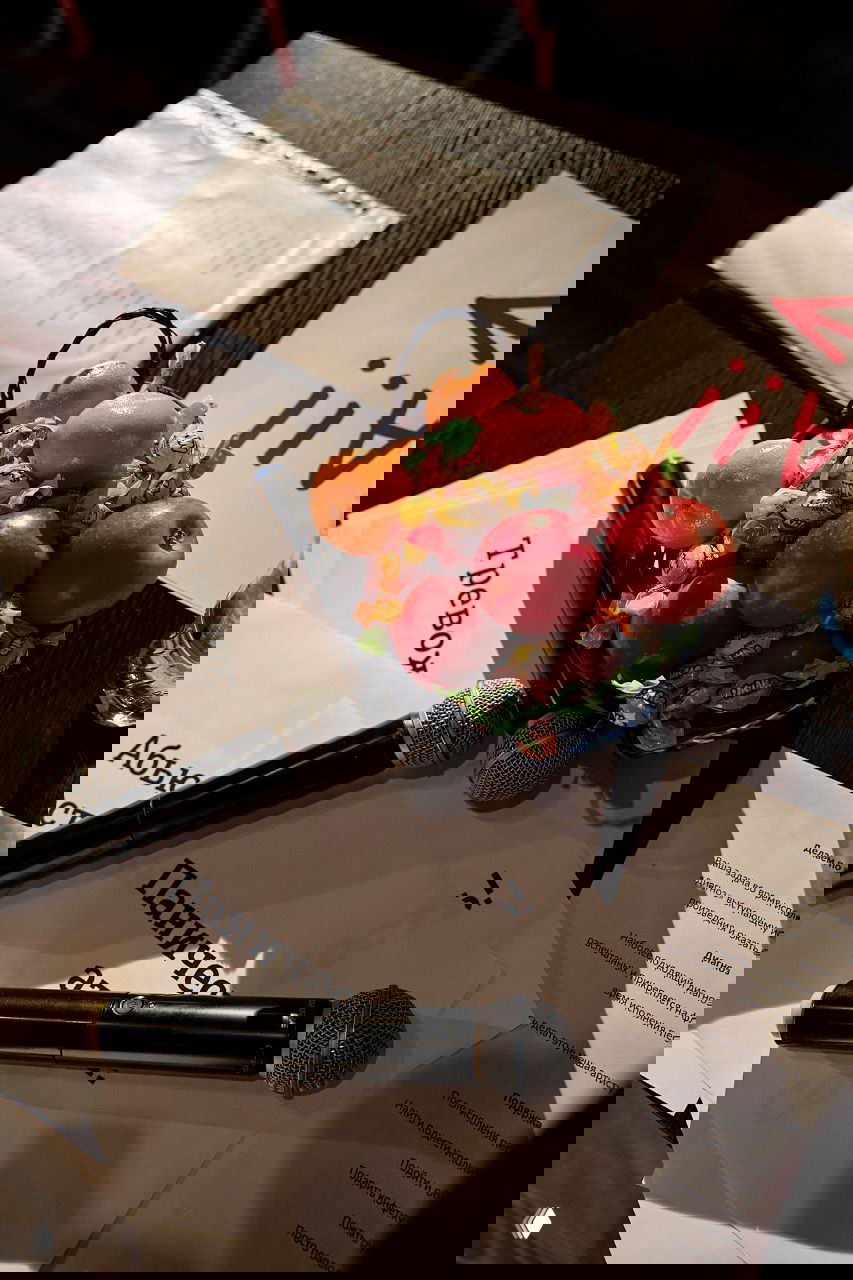 Стол с микрофонами, листами сценариев и корзиной с фруктами и конфетами — подготовка и реквизит во время мероприятия.