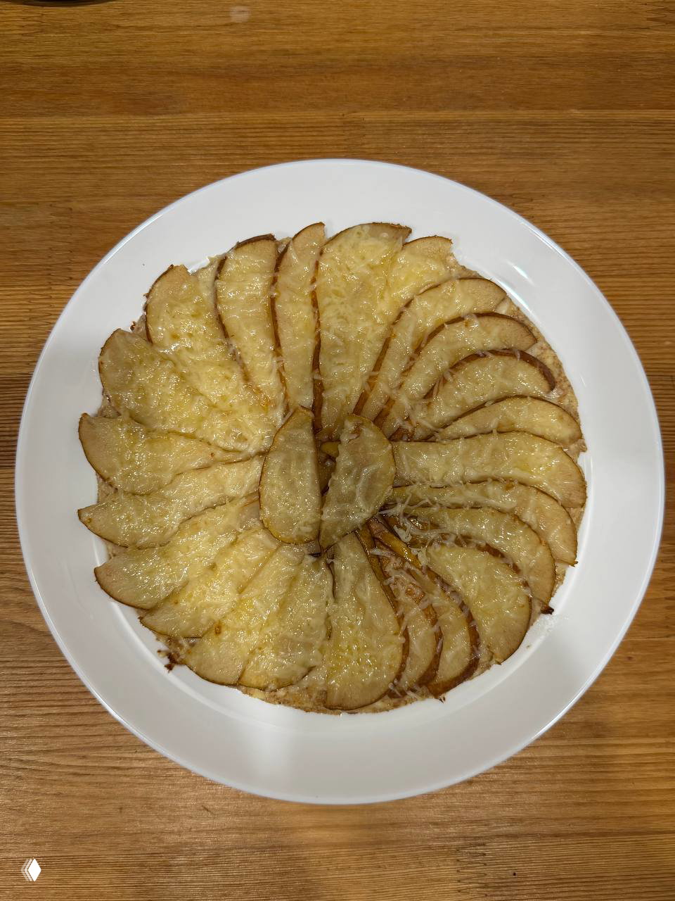 Крупный план полезной пиццы с грушей: творожная основа, ломтики груши и посыпанный сыром верх на белой тарелке