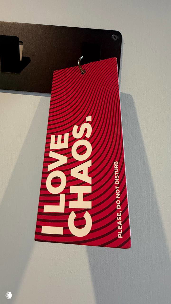 Красная карточка на дверной вешалке с надписью «I LOVE CHAOS» — фирменный слоган и дизайн-акцент в номере отеля.