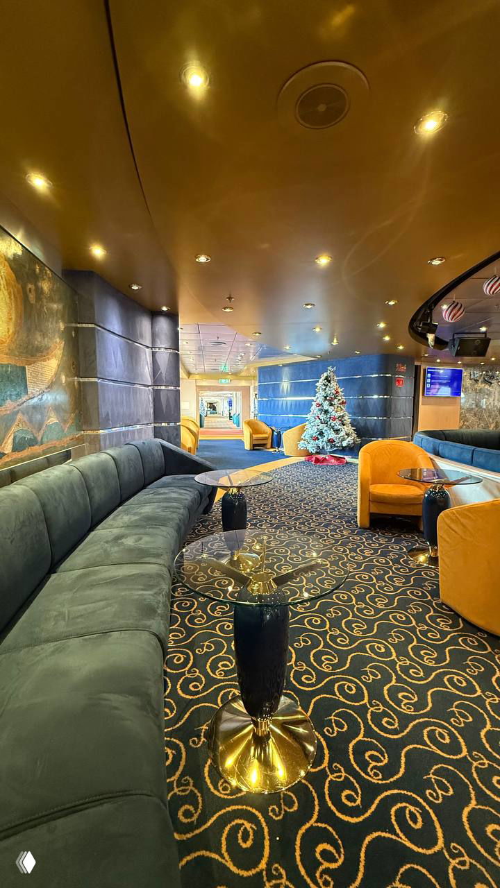 Интерьер лаунж-зоны лайнера с диванами, праздничной елкой и тёплой подсветкой — уютный общественный салон для отдыха пассажиров.